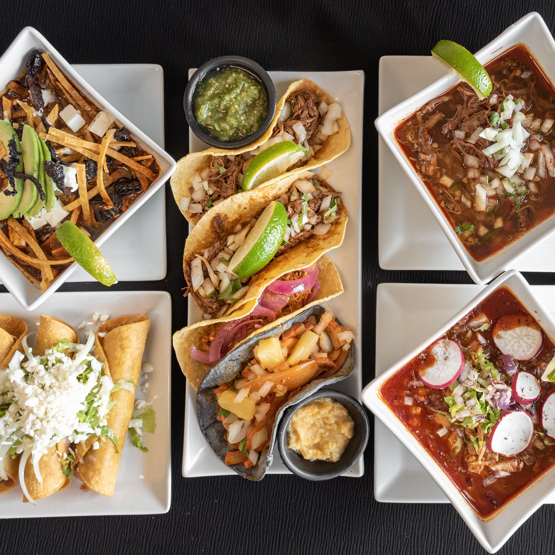 Several plates of fresh street tacos, tortilla soup, and more freshly made food